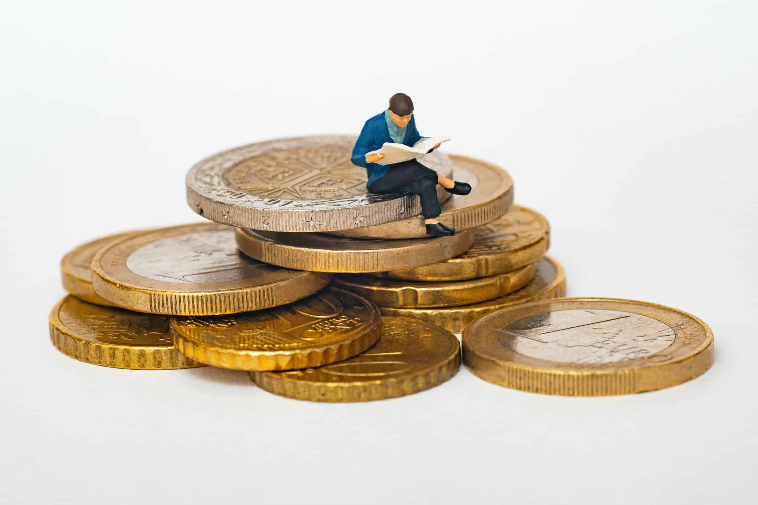 figurine of a man reading a newspaper sitting on a pile of gold coins for investing time in lead management software article