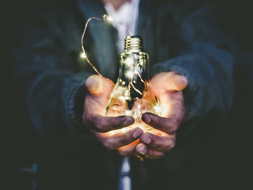 person holding a lightbulb with glowing string lights inside for growth for business article